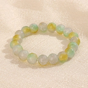 Gros plan d'un bracelet en perles dégradées de 10mm sur un fond de tissu crème satiné