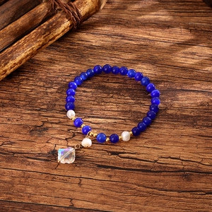 Detail of beaded bracelet with blue stones, pearls and a crystal clover charm