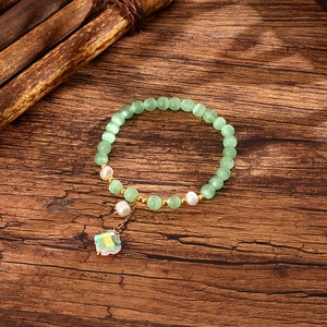 Detailed macro view of mint green cat eye stone bracelet with white pearls and flower charm
