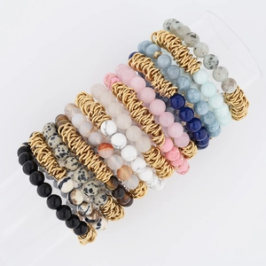 Detail of 8mm natural stone bracelets with gold spiral accents on white background