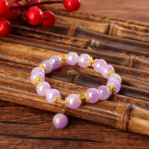 Makroaufnahme eines schillernden lila Perlenarmbands mit goldenen Blumenzwischenstücken