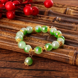 Detailansicht eines Perlenarmbands mit grünen Farbverlaufsperlen und goldenen Blumenelementen