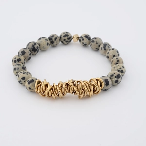 Macro shot of Dalmatian Jasper beads with stacked golden metal rings on beaded bracelet