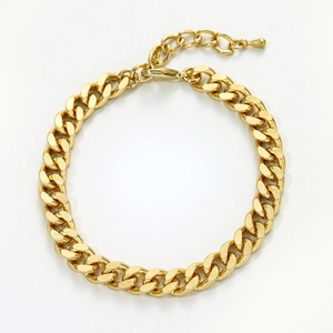 Detailed view of a gold curb chain anklet with lobster clasp and teardrop charm detail