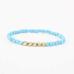 Gros plan de perles bleu clair avec cinq accents dorés irréguliers sur un bracelet minimal