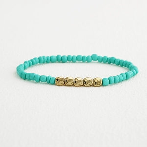 Détail d'un bracelet en perles turquoise fait main avec intercalaires dorés irréguliers