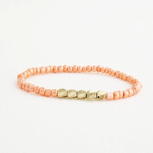 Vue détaillée des perles rose corail faites main et des accents dorés sur le bracelet