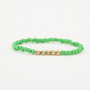 Détail de perles vertes mates et de cinq boules dorées polies sur le bracelet élastique