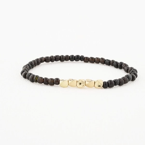 Gros plan détaillé du bracelet perlé fait main avec perles sombres et accents métalliques dorés