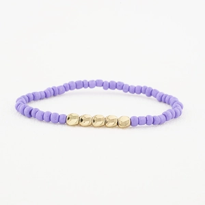Détail d'un bracelet fait main avec perles mates violettes et disques dorés brillants
