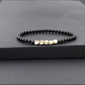 Bracelet fait main en perles noires avec cinq perles irrégulières dorées à effet martelé