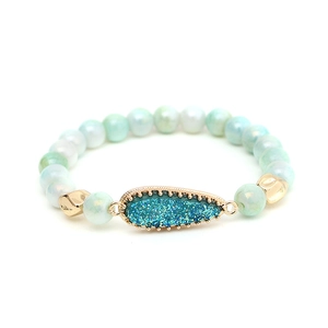 Detailaufnahme von Perlenarmband mit tropfenförmigem Anhänger und hellgrünen Perlen