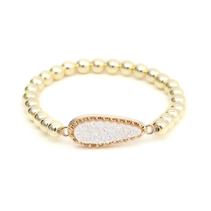 Detailed view of a gold beaded bracelet featuring a sparkling teardrop charm pendant