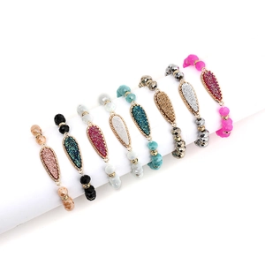 Set of 8 colorful beaded bracelets with teardrop crystal charms on white stand