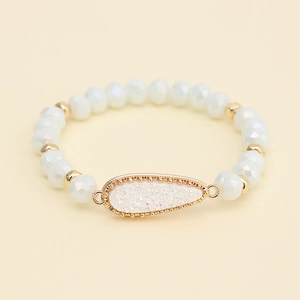 Detailed view of faceted white crystal beads and gold teardrop pendant on the bracelet