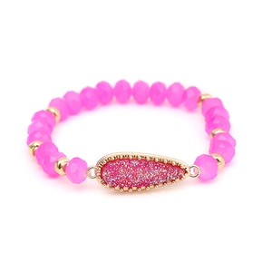 Detail view of pink crystal faceted beads and golden teardrop pendant on the women's bracelet