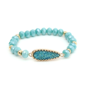 Detailed close-up of light blue beaded elastic bracelet with gold water-drop pendant