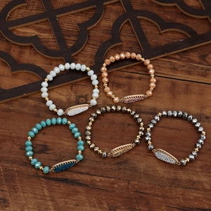 Five-piece beaded bracelet set with teardrop crystals and metallic accents on wood