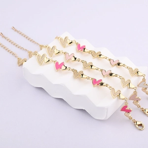 Drei goldene Herzarmbänder mit rosa Emaille und Kristallen auf einem Wellensockel