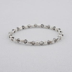 Gros plan d'un bracelet de perles bohème avec perles gris fumé et intercalaires fleurs argent
