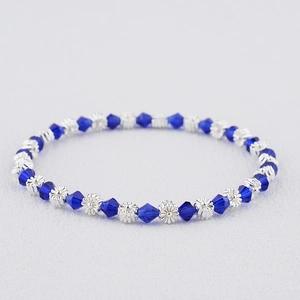 Détail macro des perles en cristal bleu roi et des perles de fleurs en argent