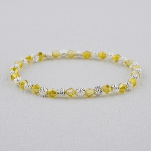 Détail macro des perles de cristal jaune et des breloques florales sur bracelet bohème