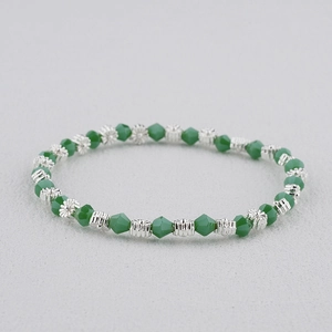 Macro détaillée de perles en cristal facetté vert et d'entretoises argentées en fleur