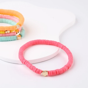 Detail of bohemian heart charm and colorful heishi clay bead stacked bracelets