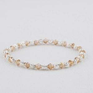 Détail d'un bracelet bohème avec perles de cristal champagne et fleurs argentées