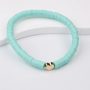 Detailed view of mint green Heishi beads bracelet with a golden heart metal charm