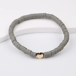 Detailed macro view of grey Heishi clay beads bracelet with a gold heart charm