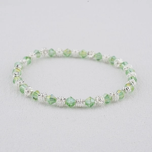 Gros plan détaillé des perles en cristal vert et des perles à fleurs argentées du bracelet