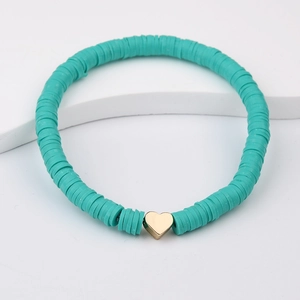 Detail of teal heishi clay bead bracelet with a gold heart charm on a white stand