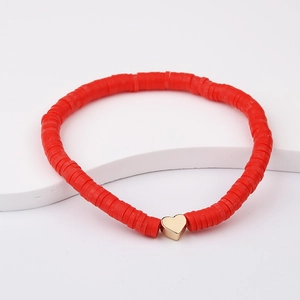 Detailed view of red polymer clay beads bracelet with a golden heart charm on white background