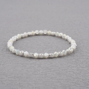 Gros plan de perles en cristal blanc et d'entretoises florales en argent sur un bracelet