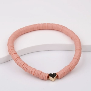 Detailed macro view of pink Heishi clay beads bracelet with a gold heart charm