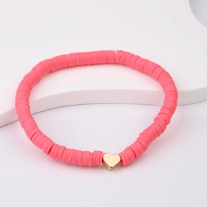 Close-up of pink heishi beads stretch bracelet with a gold heart charm on white background