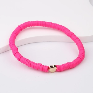 Close-up of pink polymer clay bead bracelet with a gold heart charm on a white stand