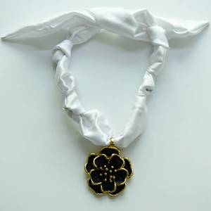 Detail of elegant black camellia pendant with gold edges on white silk ribbon necklace