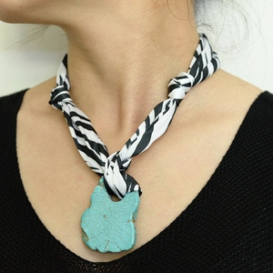 Detail of turquoise pendant necklace with black and white zebra print silk scarf