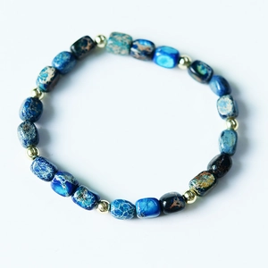 Macro detail of natural blue imperial stone beads with golden spacers on a bracelet