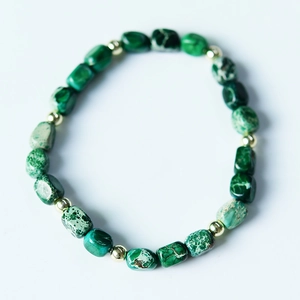 Macro view of natural green emperor stone pillar beads with gold spacer accents