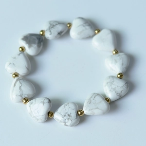Détail de perles en howlite blanche en forme de cœur avec de petites entretoises dorées