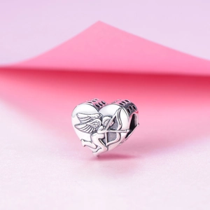 Dettaglio macro dello charm a cuore in argento S925 con rilievo Cupido e intagli laterali