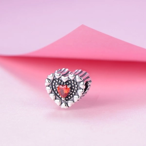 Dettaglio macro dello charm cuore in argento sterling S925 con gemma rossa per bracciali
