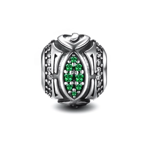 Macro shot of S925 silver charm with green gemstones and vintage filigree details