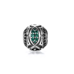 Macro detail of vintage S925 silver charm bead with emerald green stones and black crystals