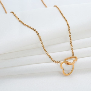 Elegant gold double interlocking heart necklace on white silk fabric background