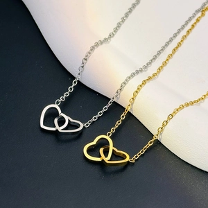 Close-up of interlocking heart pendants in gold and silver finish with polished metal chains