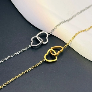 Close-up of interlocking heart-shaped double pendants in gold and silver finish